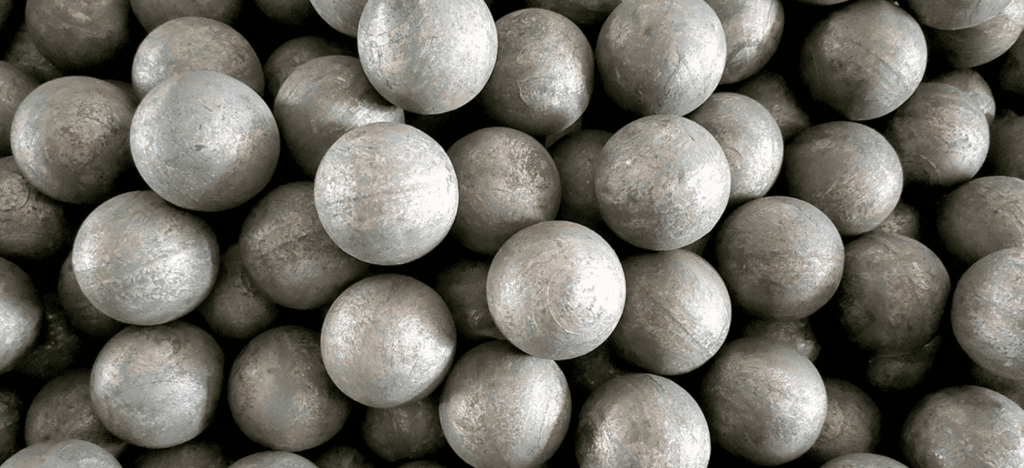 A pile of large steel balls, neatly stacked, with a smooth surface, reflecting the surrounding light and showing the texture of metal.