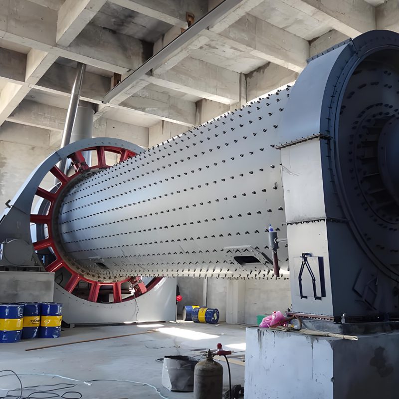 A large cement ball mill operating in an industrial factory setting, showcasing its robust structure and machinery.