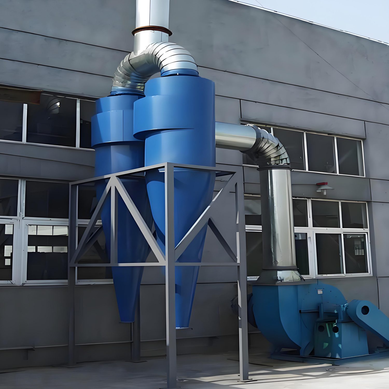 A blue cyclone dust collector next to an exterior building, demonstrating an efficient industrial ventilation system