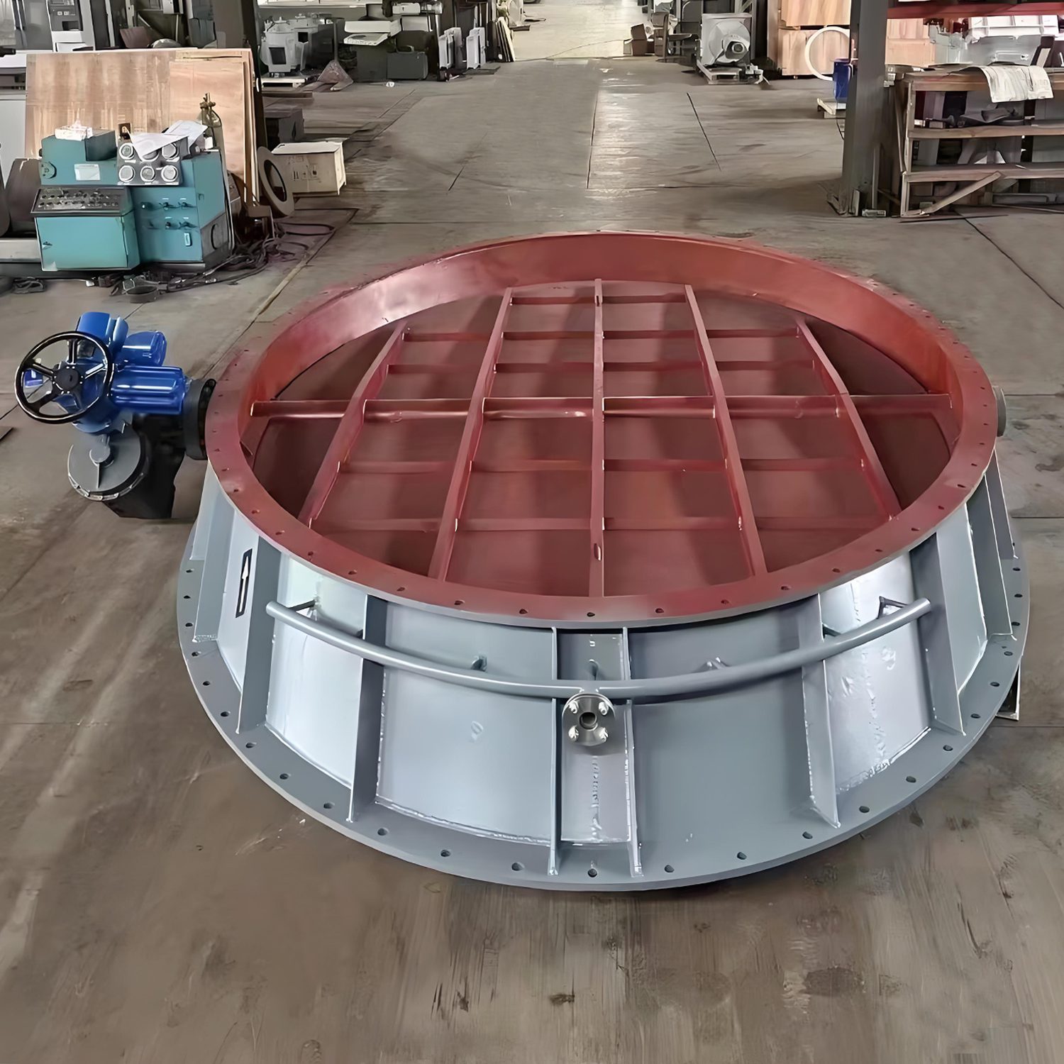 A factory setting showcasing a large circular metal plate equipped with an electric tilt shutter valve for enhanced functionality.