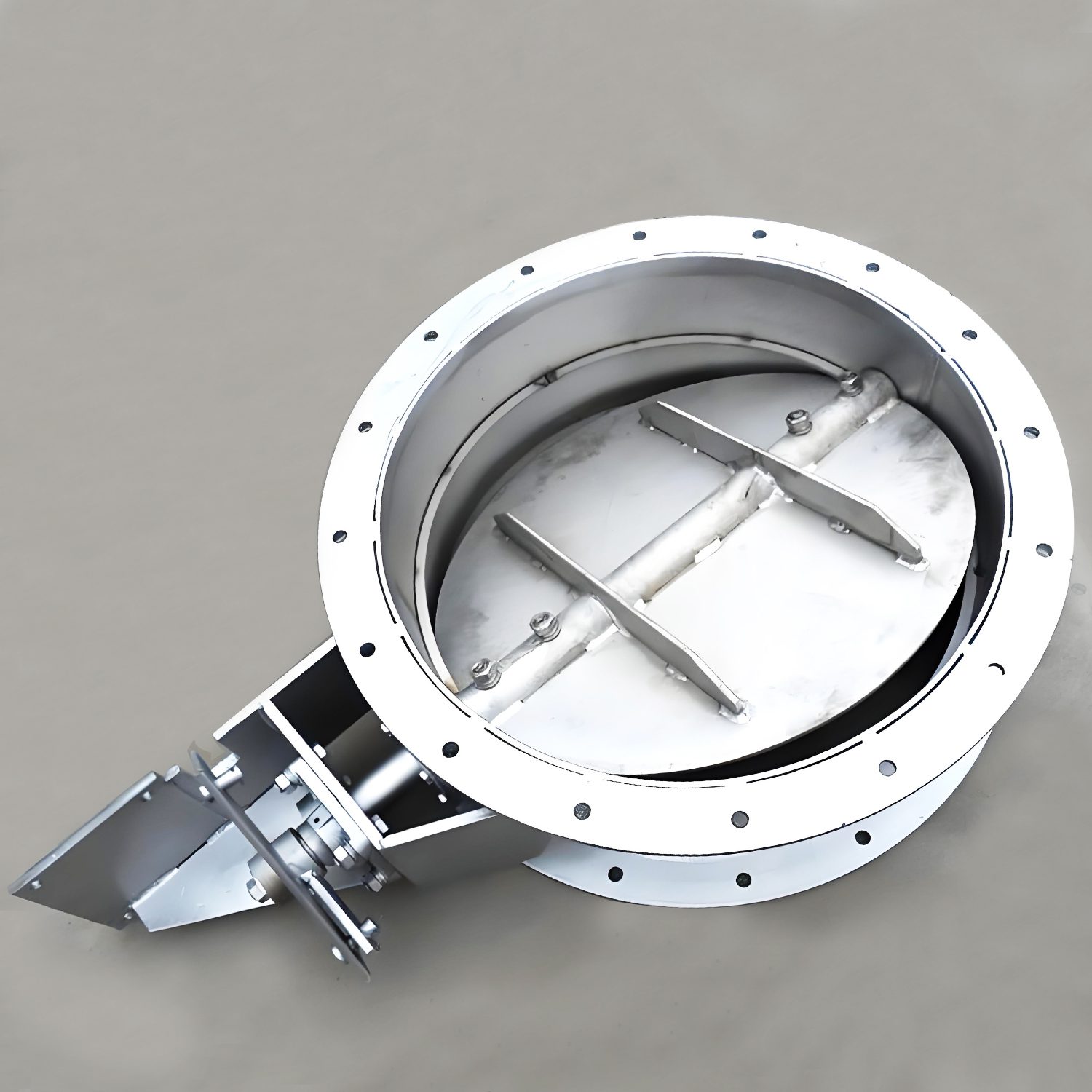 A stainless steel butterfly valve resting on the ground, highlighting its robust construction and functional design.